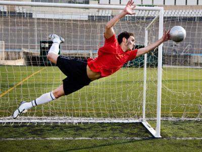 In this image, the goalie is blocking the ball from the net. what is his role on the team?